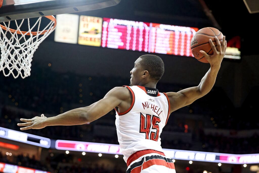 Donovan Mitchell mid-air dunk in number 45 jersey on vibrant red and white basketball court wallpaper
