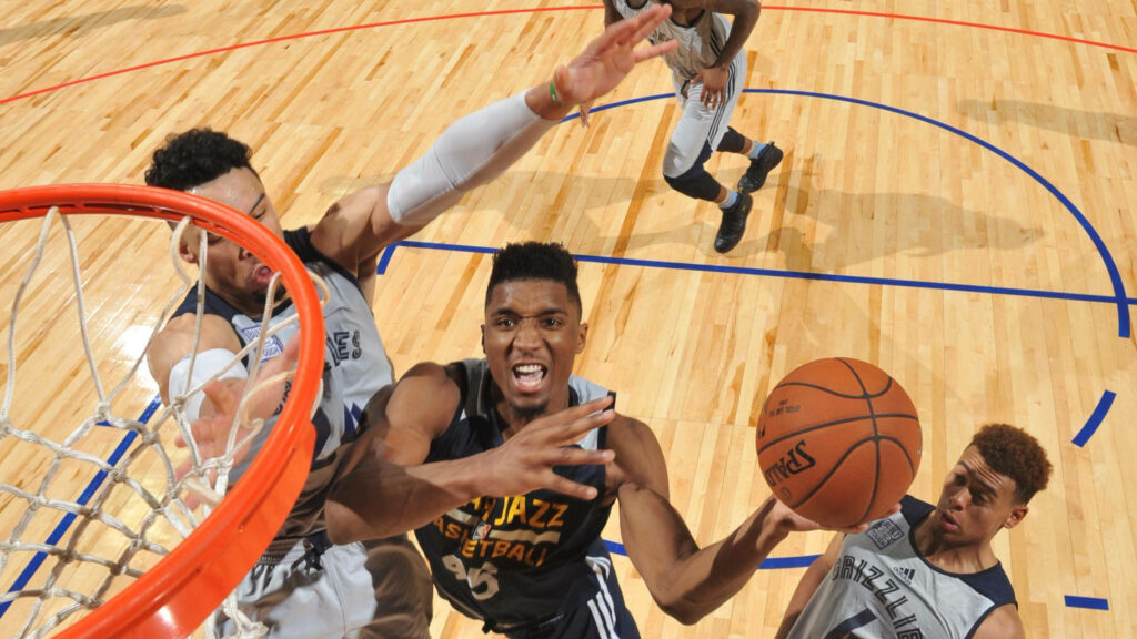 Donovan Mitchell driving to basket mid-action with defenders on polished hardwood court wallpaper
