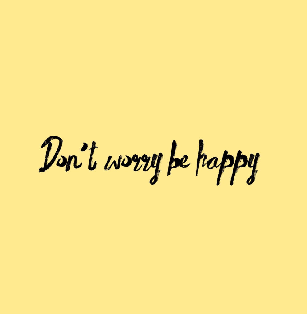 Cheerful Don't Worry Be Happy handwritten text on soft yellow background inspiring positivity wallpaper