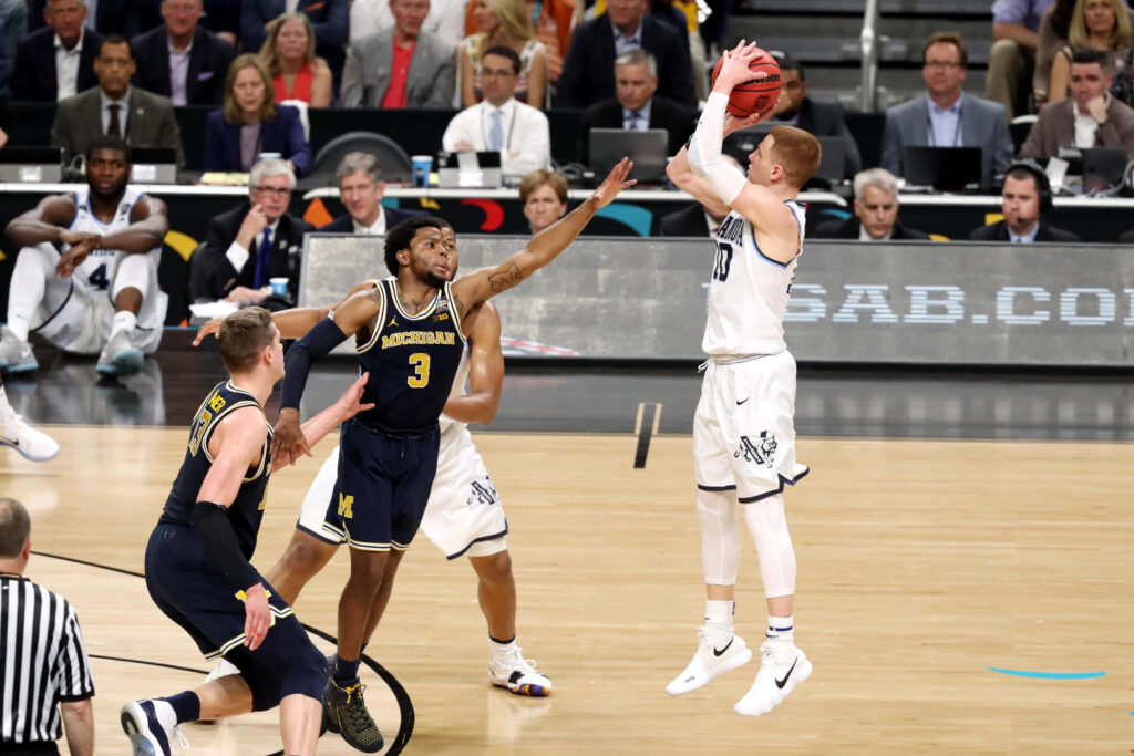 Donte DiVincenzo Villanova shooting over Zavier Simpson Michigan in intense college basketball game Wallpaper