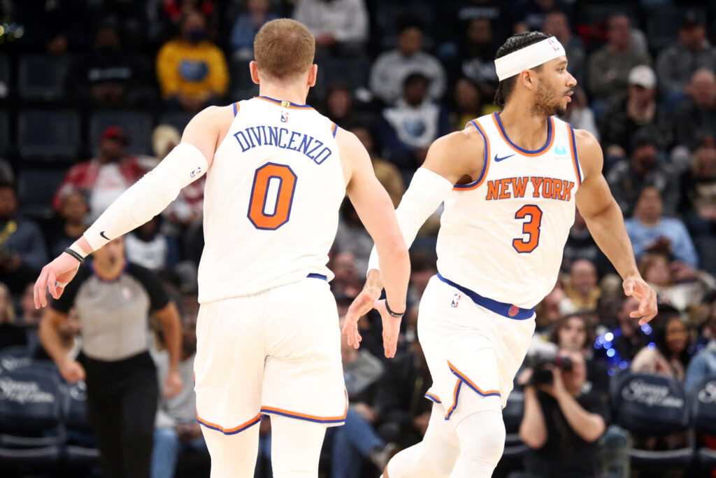 Donte DiVincenzo and Josh Hart Knicks players in white uniforms mid-game on bright court crowd background Wallpaper