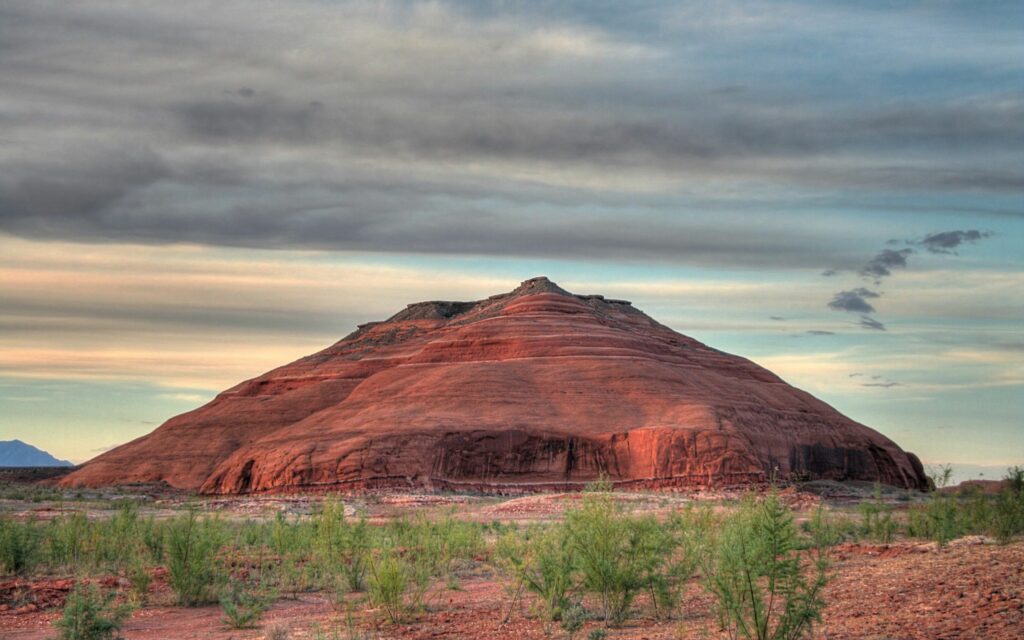 Dormant volcano under warm red summer sky with green vegetation and smooth volcanic slopes Wallpaper