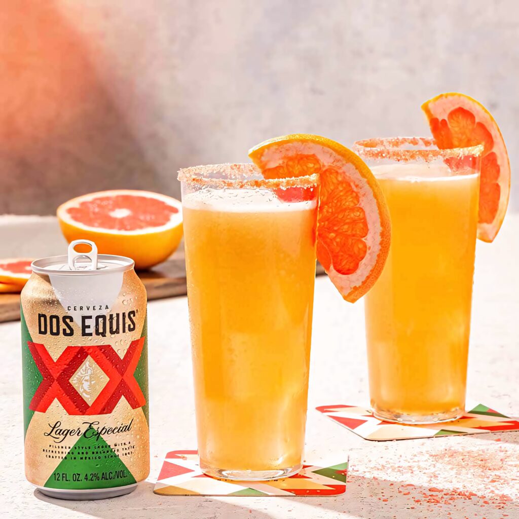 Two tall Dos Equis beers with grapefruit slices and salted rims on sunlit summer background Wallpaper