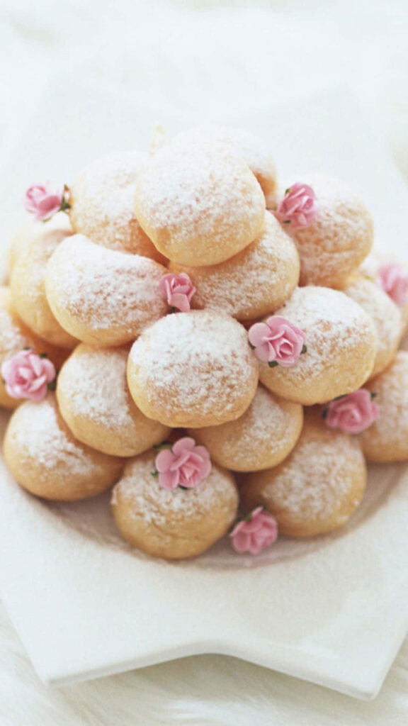 Sugar-Coated Delights: Colorful Doughnuts Adorned with Pink Floral Candy on Desserts Backdrop Wallpaper