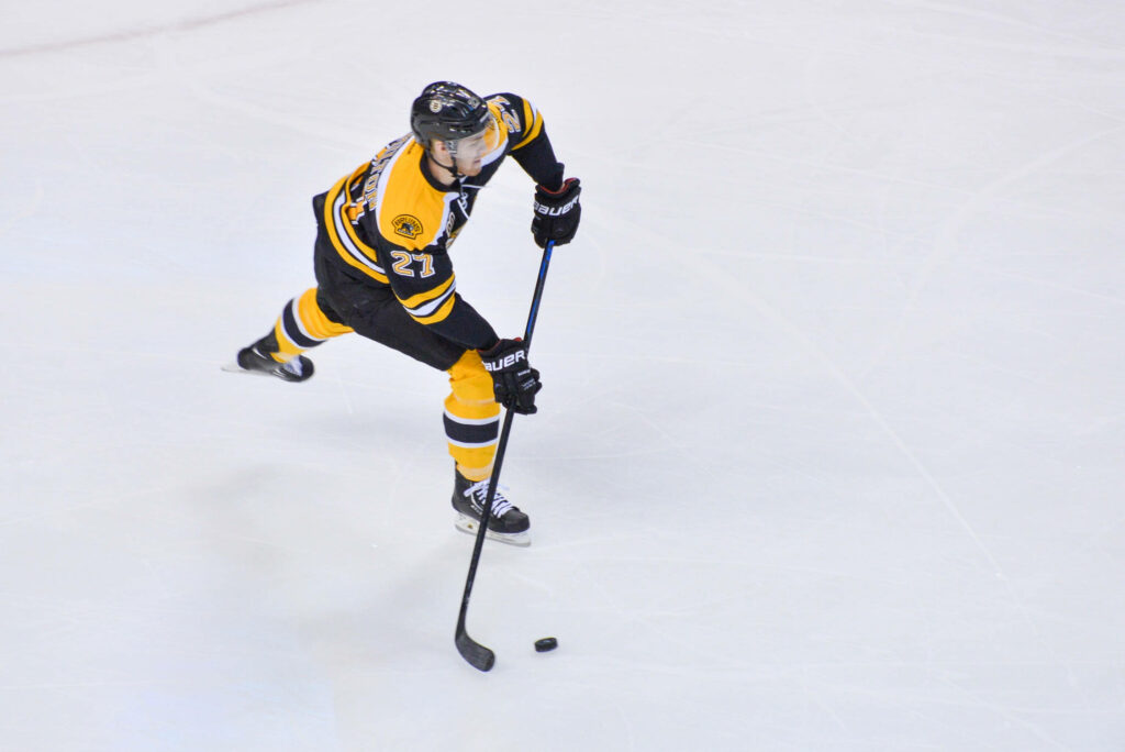 Dougie Hamilton Boston Bruins black gold uniform skating fast in intense NHL game vs Maple Leafs Wallpaper