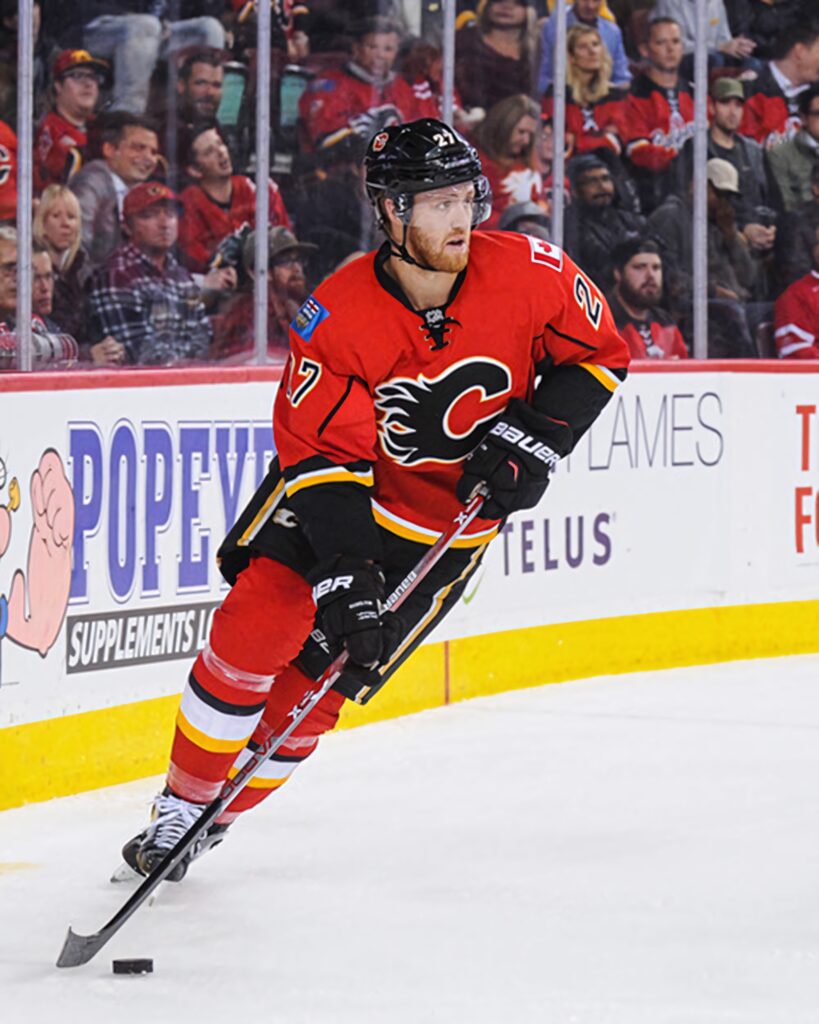 Dougie Hamilton skating in Calgary Flames jersey during fast-paced game against Edmonton Oilers Wallpaper
