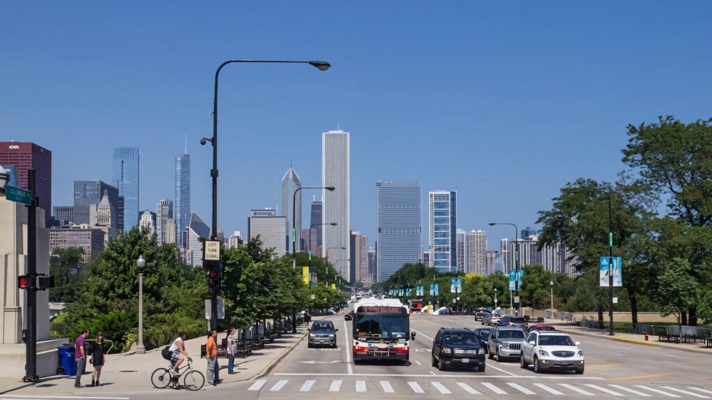 Downtown Chicago busy street with pedestrians cyclists iconic skyscrapers and green trees background Wallpaper