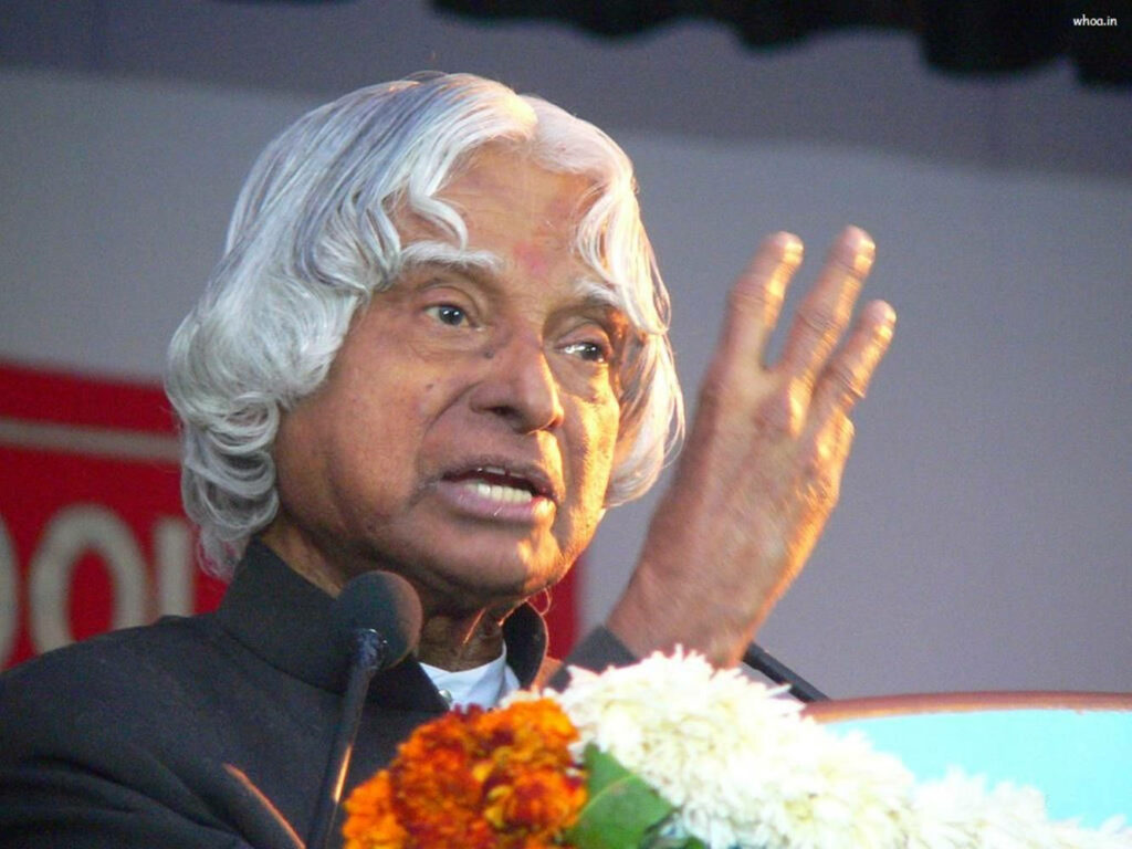 Dr Abdul Kalam delivering inspiring lecture with vibrant flowers background motivational leader Wallpaper
