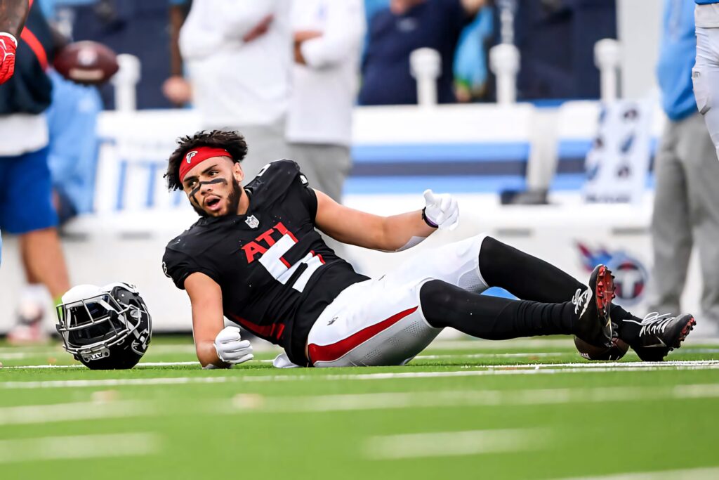 Atlanta Falcons wide receiver Drake London in black red uniform on bright green turf intense action Wallpaper