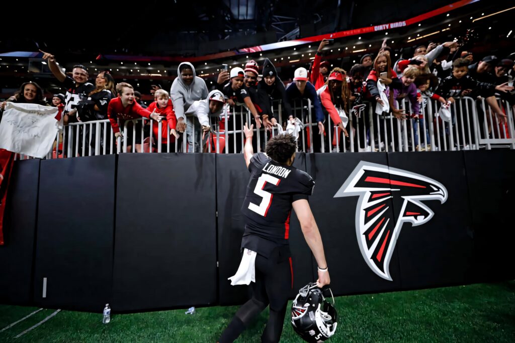 Drake London of Atlanta Falcons engaging fans over stadium barrier in vibrant team colors Wallpaper