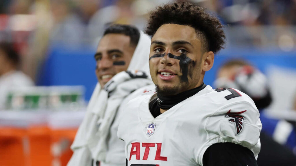 Drake London Atlanta Falcons in white red uniform with black eye paint on NFL game day sidelines Wallpaper