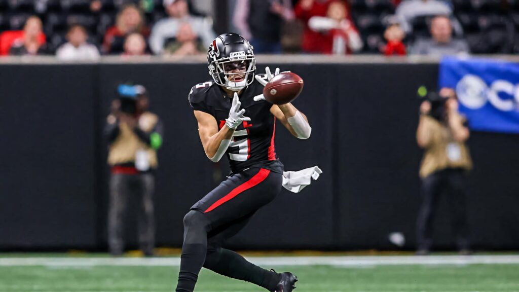 Drake London catching football in black and red uniform with intense focus in stadium action Wallpaper
