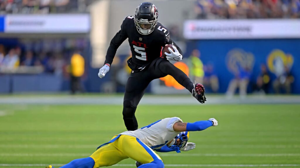 Drake London in Atlanta Falcons uniform leaps over defender in intense football game action Wallpaper