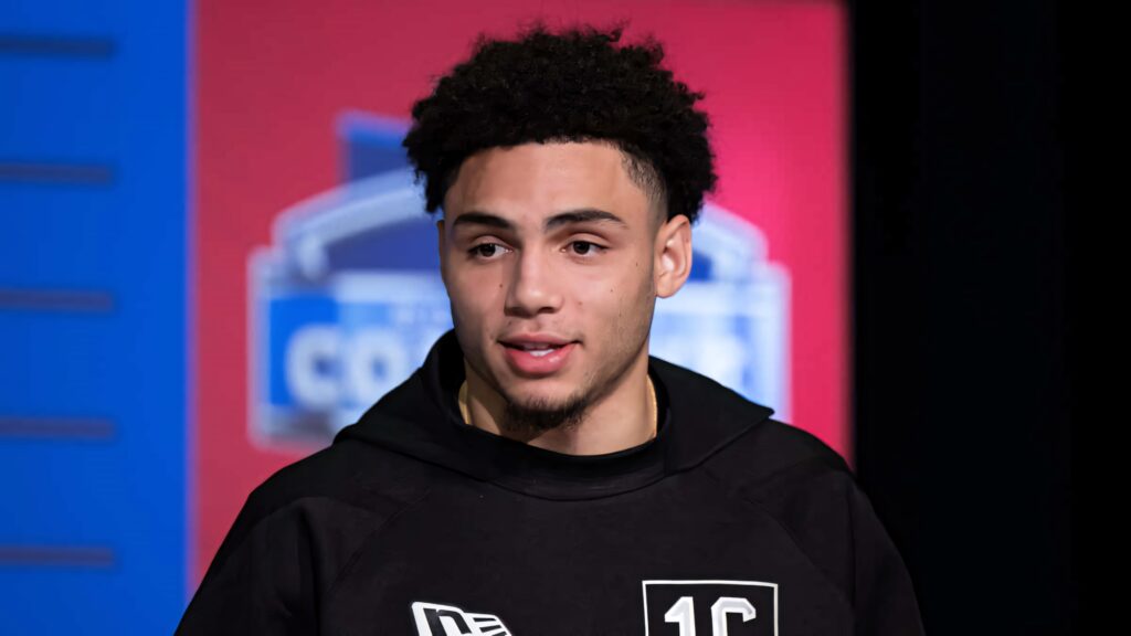 Drake London in black athletic hoodie at sports press conference with red and blue background Wallpaper