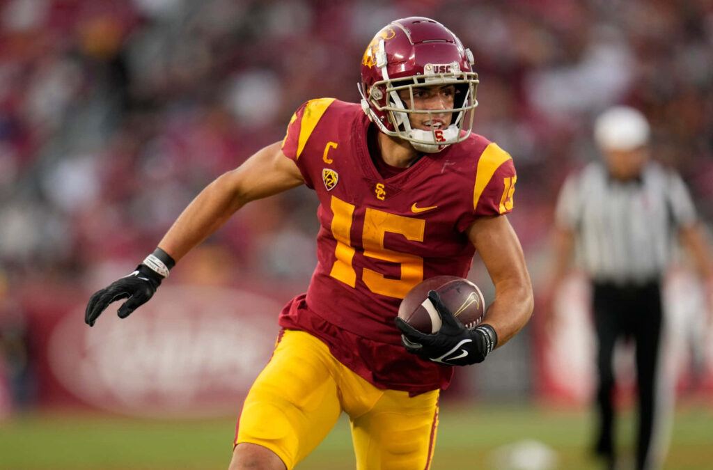 Drake London in USC Trojans uniform sprinting with football during intense stadium game action Wallpaper