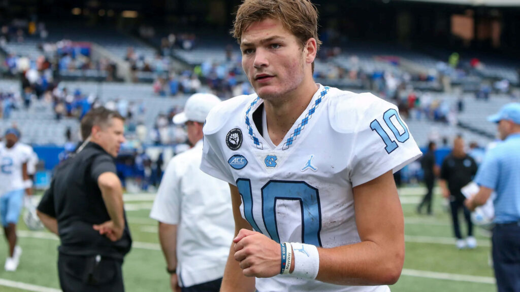 Drake Maye in UNC football jersey number 10 on field after game with vibrant stadium background Wallpaper