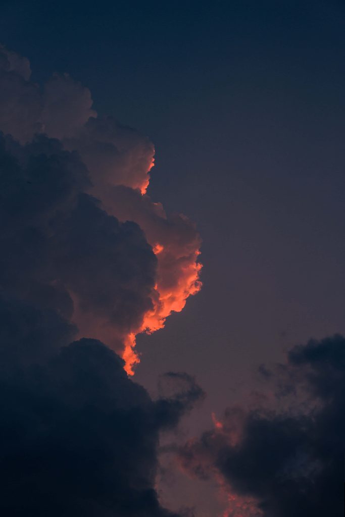 Dramatic 4K sunset clouds with fiery orange edges and dark blue twilight sky wallpaper background