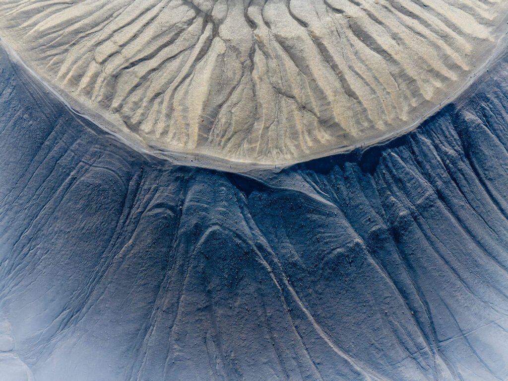 Aerial view of crater with textured geological details in earthy beige and deep charcoal tones Wallpaper