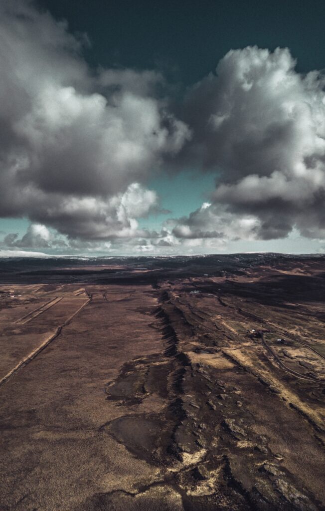 Aerial view of rugged open land with dramatic clouds deep shadows and earthy textured landscape Wallpaper