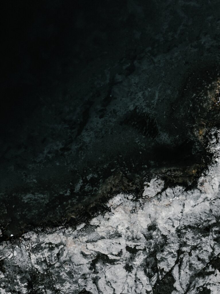 Aerial view of dark ocean meeting rugged icy shore dramatic nature landscape wallpaper background