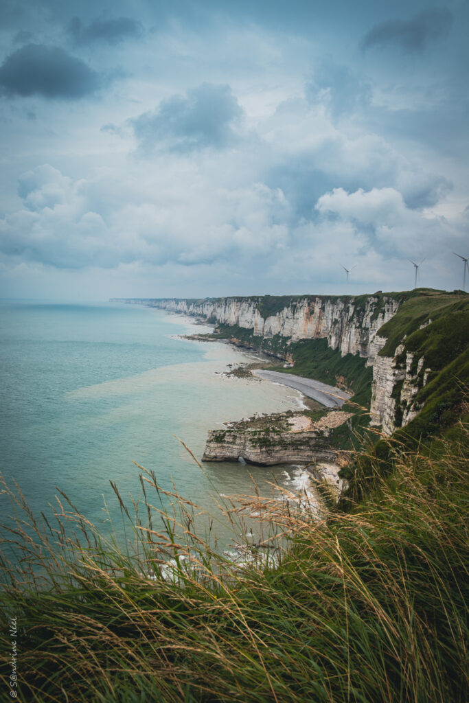 Aerial view of white cliffs and turquoise sea with rocky coast under moody cloudy sky wallpaper