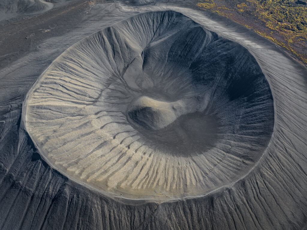Aerial view of volcanic crater with textured ridges and shadows in gray earth tones wallpaper