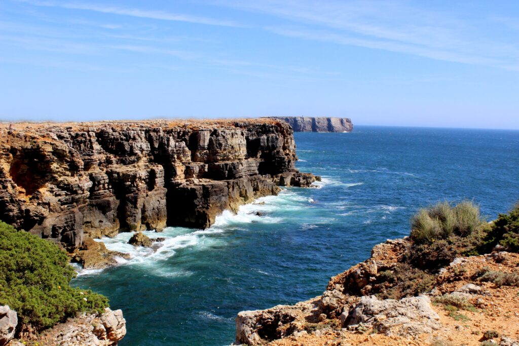 Dramatic Algarve coastline with rugged cliffs and deep blue ocean under clear sky wallpaper