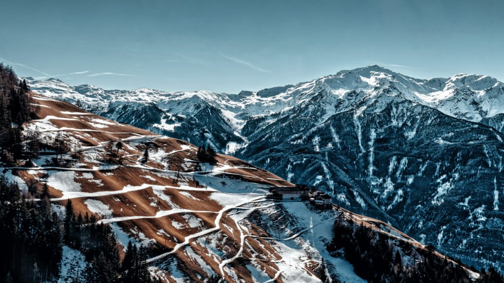 Alps mountain wallpaper with snowy peaks rugged slopes and clear blue sky high altitude landscape