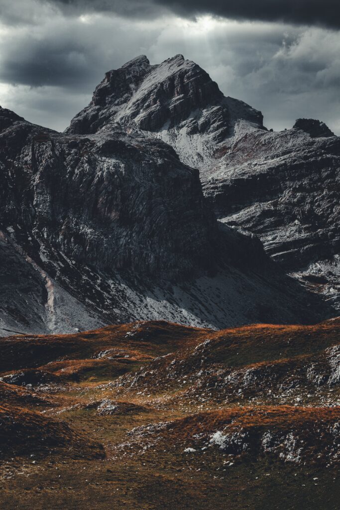 Dramatic alpine landscape with rugged mountains autumn hills and moody sky wallpaper background