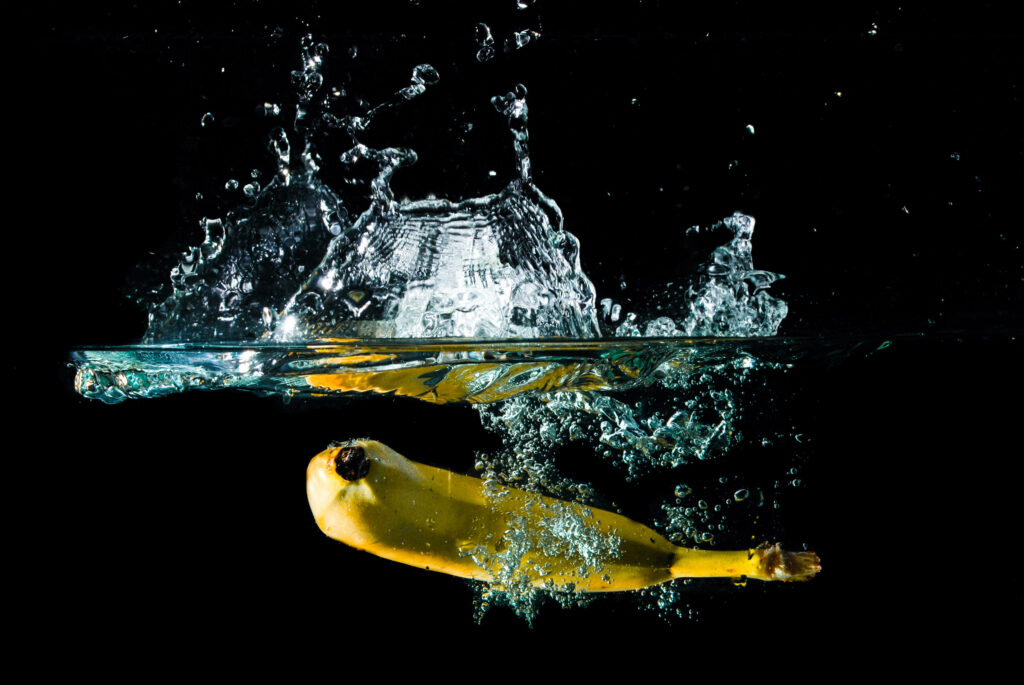 Banana splashing underwater with vivid detail against dark background wallpaper background