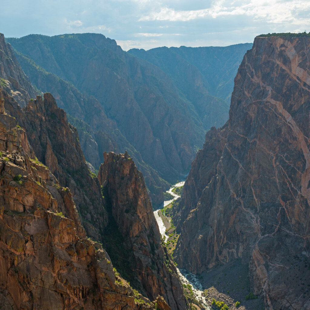 Dramatic Black Canyon Colorado cliffs illuminated by sunlight showcasing rugged winding gorge landscape Wallpaper