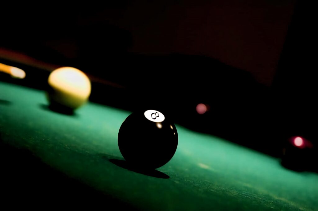 Sharp black eight ball on green pool table with dark moody background billiards wallpaper