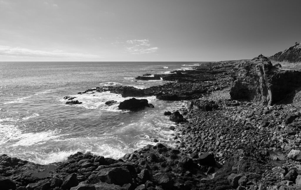 Black and white coastal wallpaper with rugged rocky shoreline and dramatic sea waves background