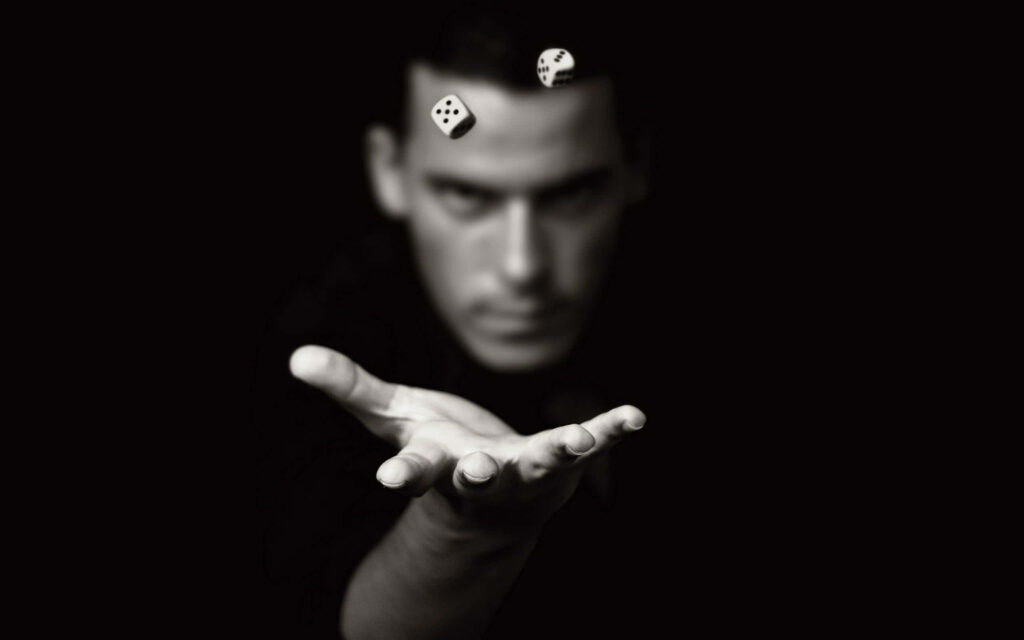 Black and white wallpaper of man tossing floating dice in motion with blurred background and shadows