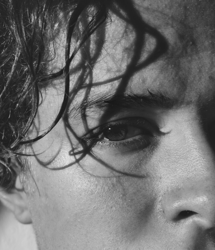 Black and white close up of male face with intense eye wet hair and textured skin dramatic portrait Wallpaper