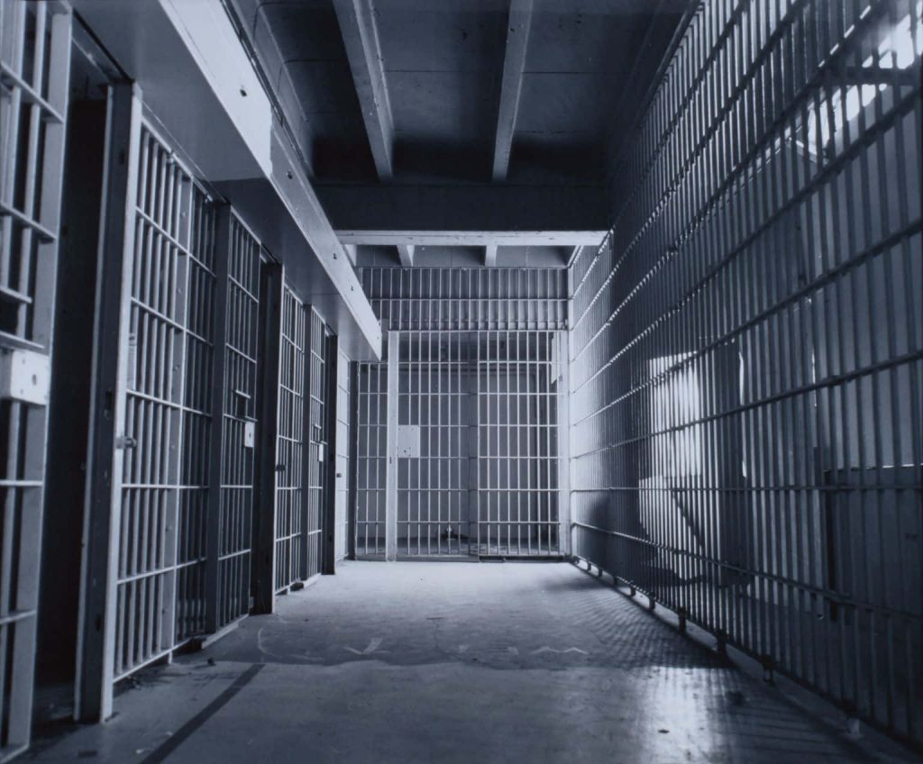 Black and white prison corridor wallpaper with heavy metal bars and high contrast lighting background