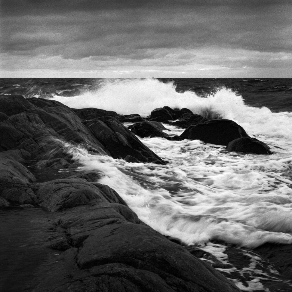 Striking Black and White Sea Wallpaper: Waves Crashing on Stone
