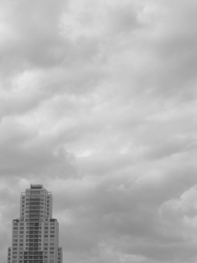Monochrome Sky Wallpaper: Dramatic Clouds Over Tall Building