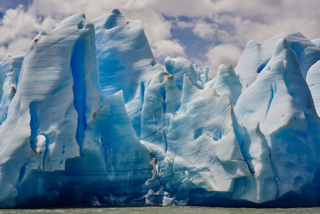Close-up of towering blue icebergs and textured ice floes reflecting cool tones under sky Wallpaper