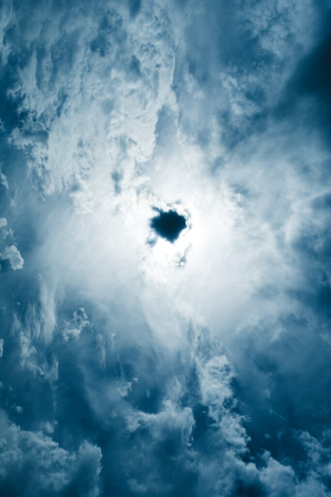 Dramatic textured porous clouds with vibrant blue sky and radiant sunlight shining through opening Wallpaper