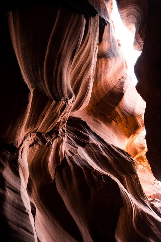 Dramatic canyon cave wallpaper with swirling sandstone walls illuminated by natural light beams