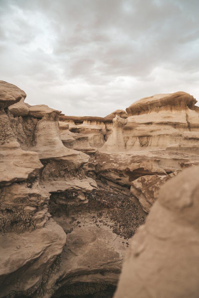 Dramatic canyon landscape with rugged rocks towering cliffs and layered mountains under clouds Wallpaper