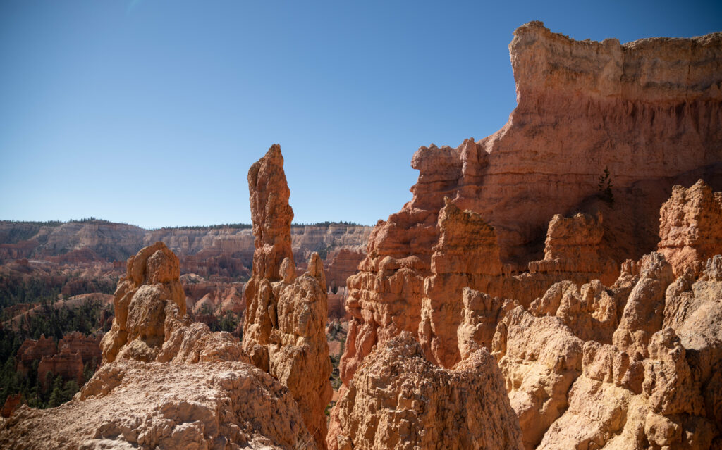 Dramatic canyon landscape with towering orange red rock formations under clear blue sky wallpaper