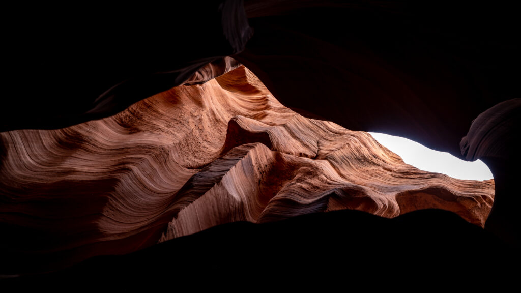 Dramatic canyon wallpaper with textured rock formations and rich earth tones in deep shadows