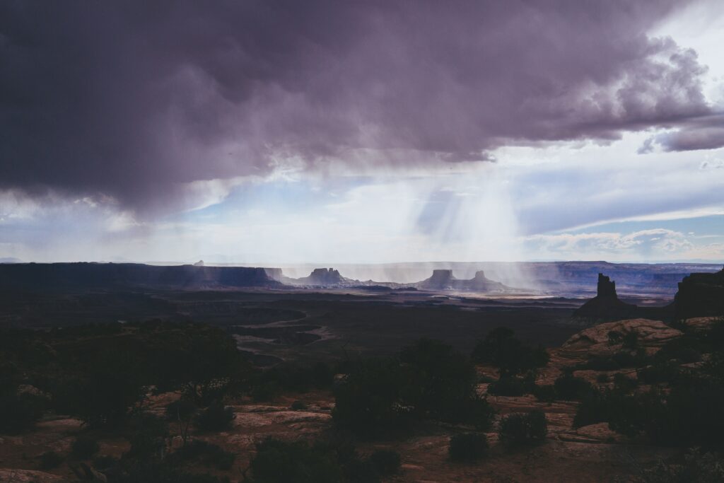Dramatic Canyonlands National Park landscape with rugged rock formations and sunbeams breaking clouds Wallpaper