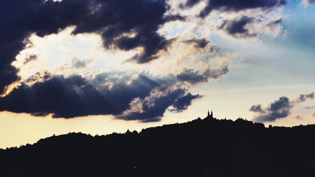 Silhouette of Kaisergasse castle on hill under dramatic cloudy sky in Linz Austria wallpaper background