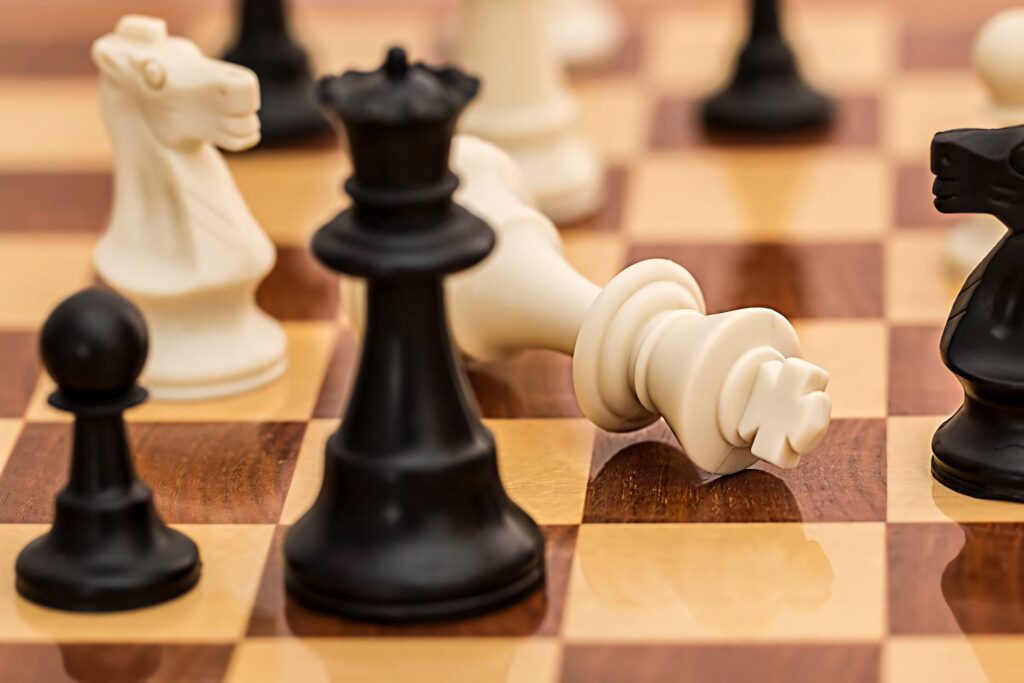 Dramatic chess scene with toppled White King and Black Queen on polished wooden board wallpaper
