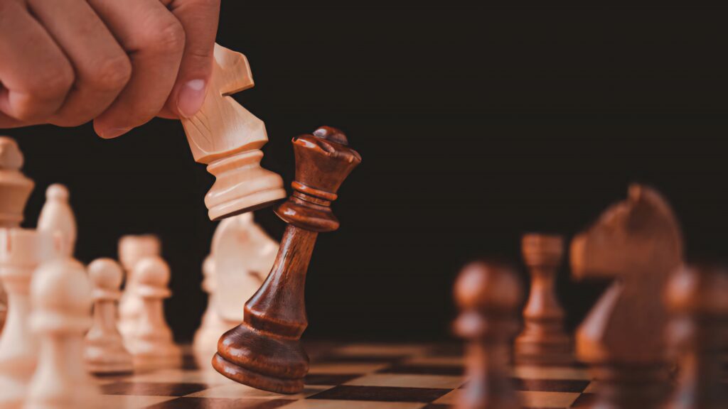Hand holding light wooden knight captures detailed brown queen on black background chess scene Wallpaper