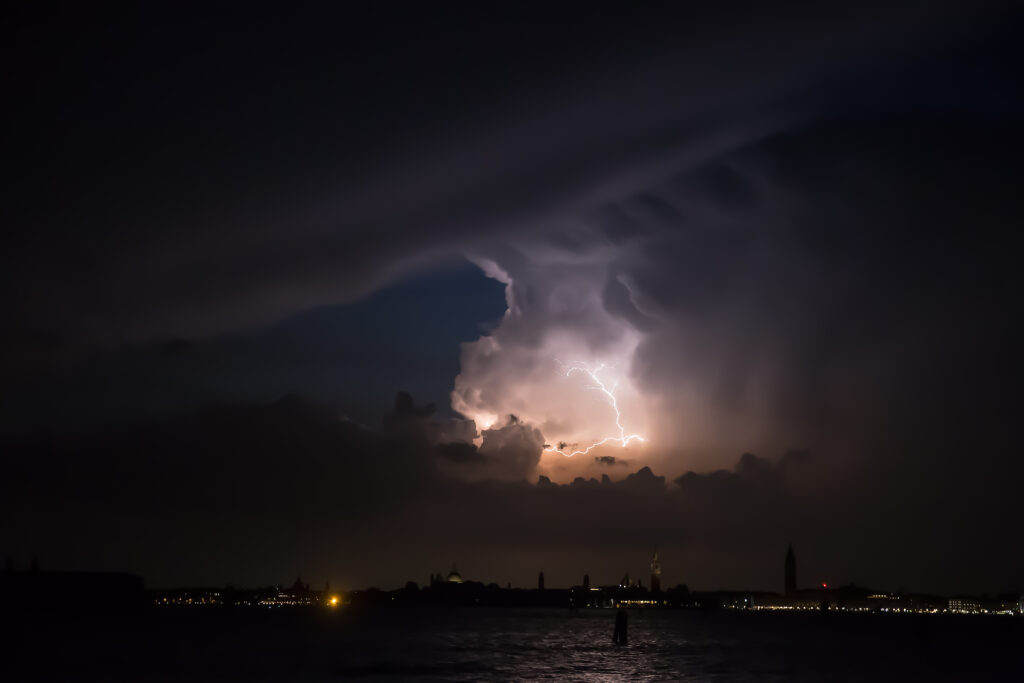 City skyline with lightning storm dark clouds and water reflections dramatic wallpaper background
