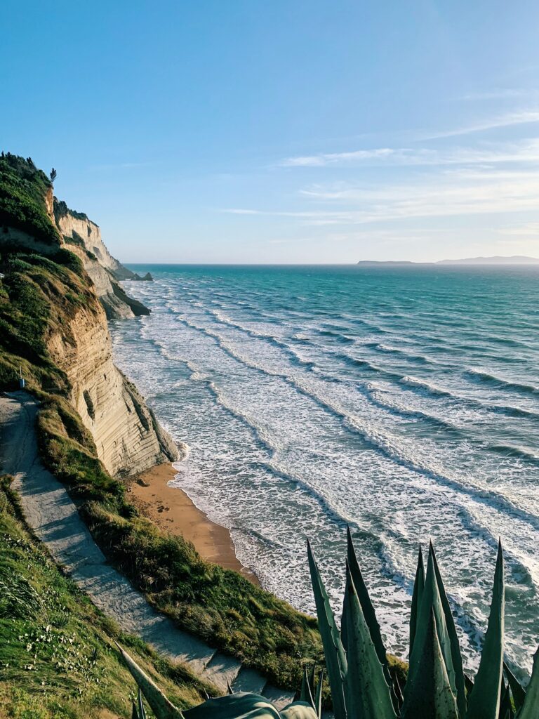 Dramatic cliffs with turquoise sea and sandy cove under clear blue sky scenic coastal path wallpaper
